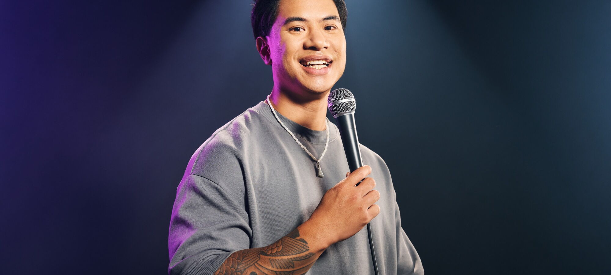 Tutty Tran mit Mikro vor grauem Hintergrund