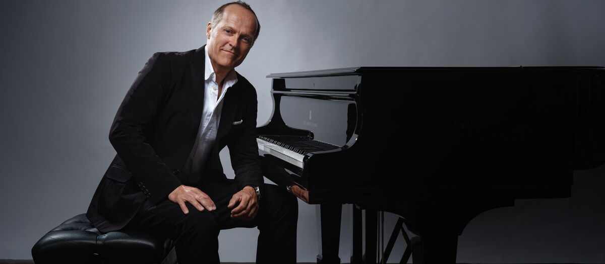 Joja Wendt sitzt in einem Schwarzen Anzug an einem Klavier