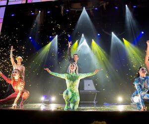Magier mit 3 Tänzerinnen auf der Bühne mit buntem Licht
