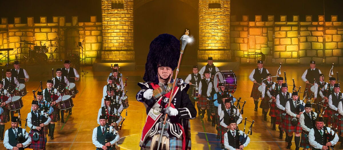 Trommler:innen, Dudelsackspieler:innen auf einer Bühne vor einer Burgmauer