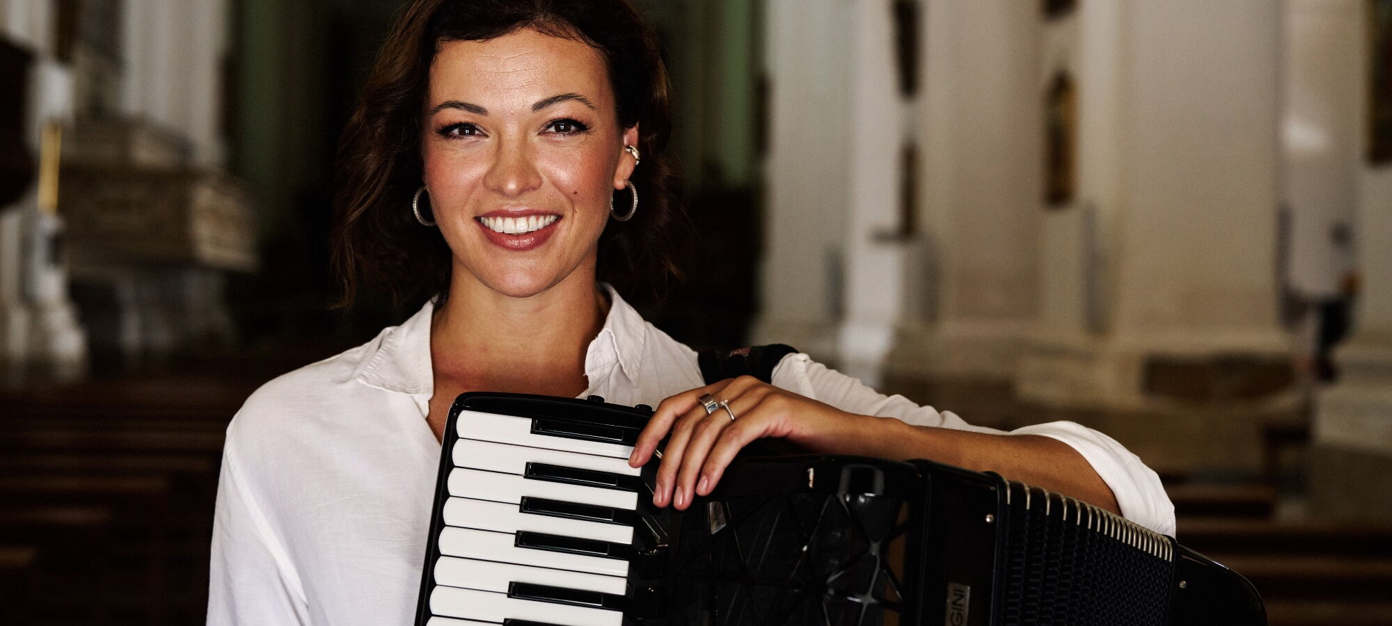 Ksenija Sidorova mit ihrem Akkordeon in die die Kamera lächelnd.