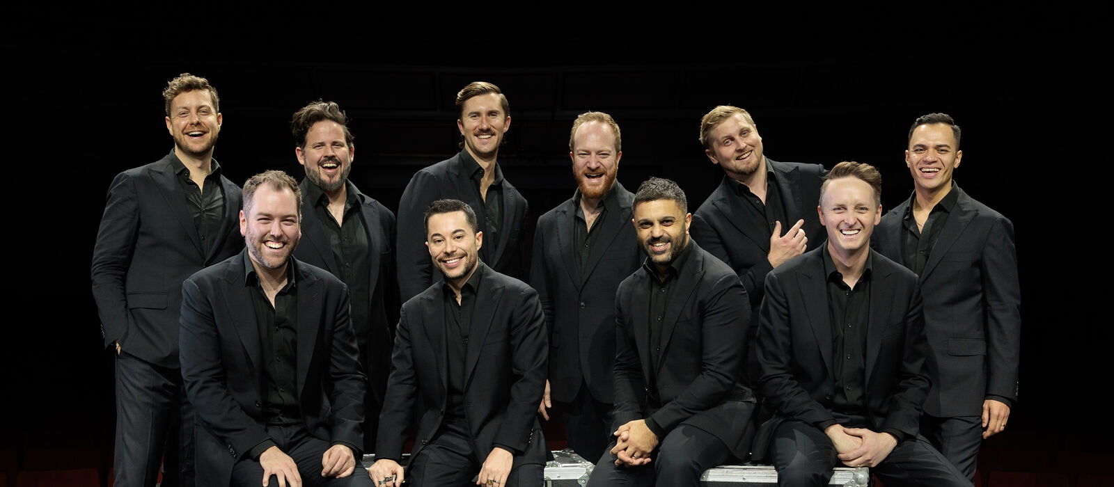 The TEN TENORS auf Cases auf der Bühne sitzend