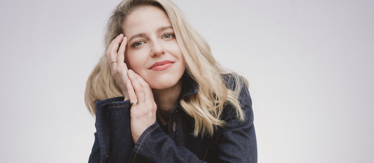 Karina Canellakis auf Hände gestützt in die Kamera blickend.