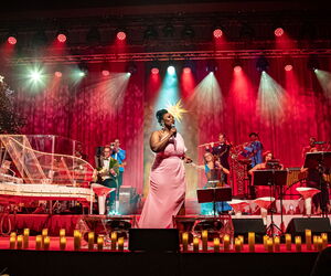 Max and Friends auf der Bühne und spielen Instrumente und singen. Die Bühne ist weihnachtlich geschmückt.