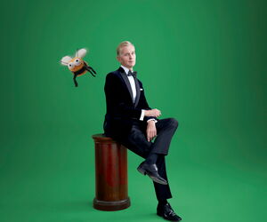 Max Raabe vor grünem Hintergrund sitzend mit Hummel