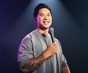 Tutty Tran mit Mikro vor grauem Hintergrund