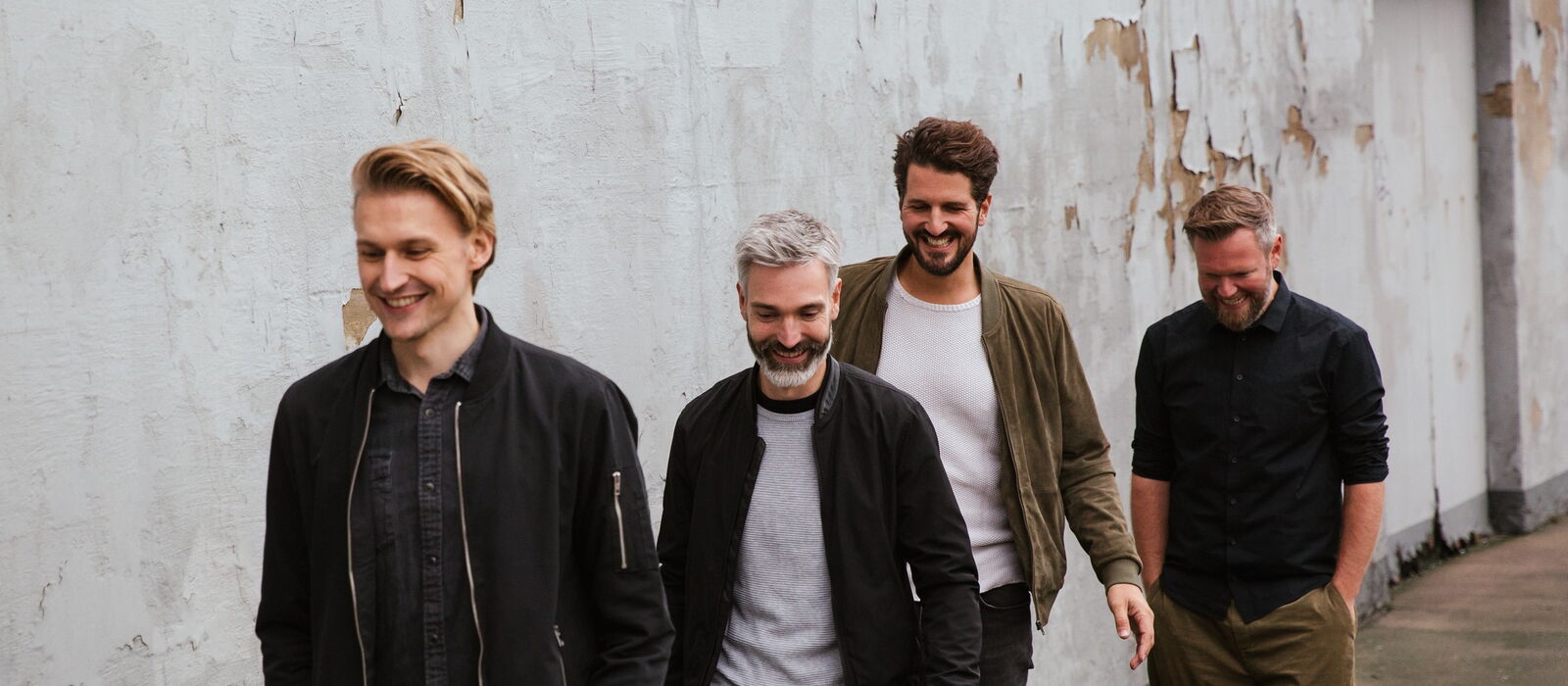 Die Bandmitglieder von Jeden Tag Silvester auf einem Bürgersteig hintereinander laufend.