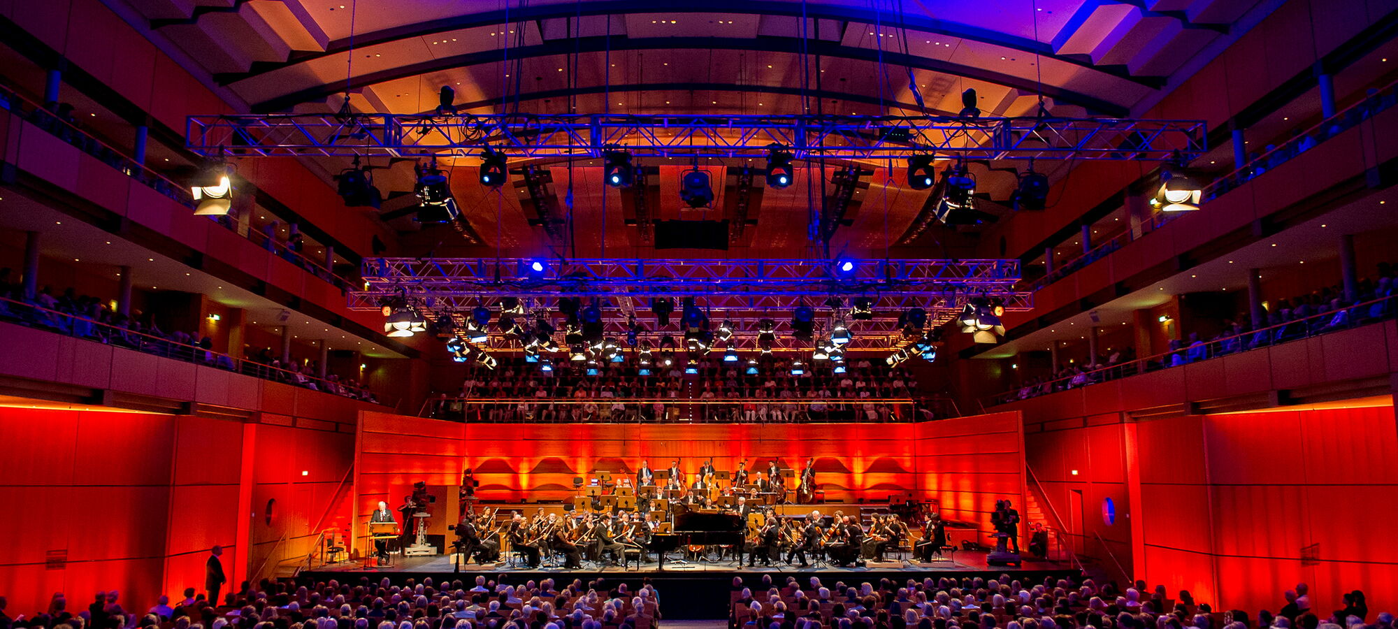 Voller Konzertsaal beim Orchesterkonzert mit bunter Beleuchtung
