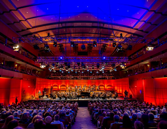 Voller Konzertsaal beim Orchesterkonzert mit bunter Beleuchtung