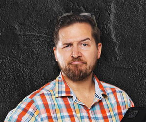 Clemens Brock mit einem Handy in der Hand auf einem dunklem Hintergrund